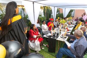 People gather under a white canopy tent for an outdoor celebration with tables and decorations.