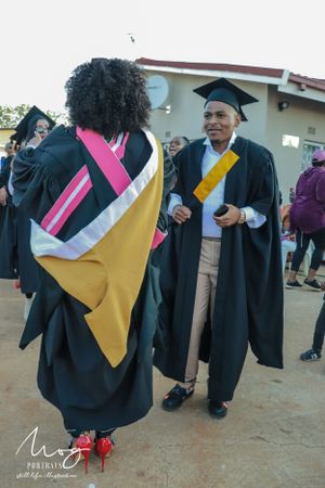 Graduates in academic regalia celebrate at commencement ceremony, wearing colorful academic stoles and graduation gowns.