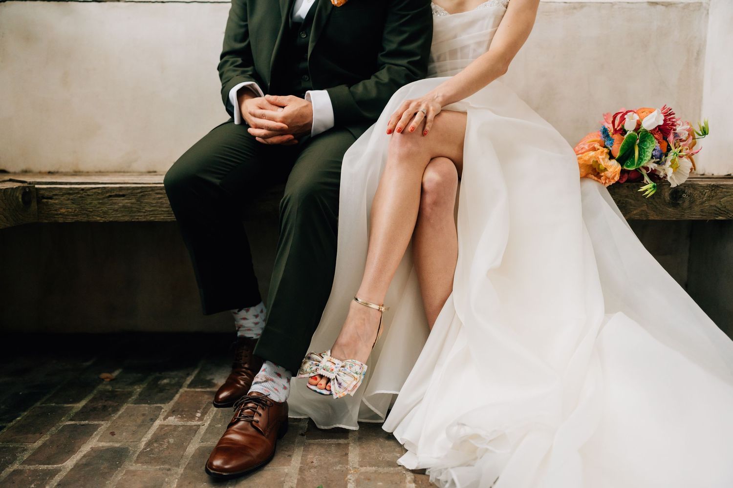 A romantic wedding couple embraces under a rustic stone archway framed by green ivy and brick in Race + Religious' New Orleans courtyard