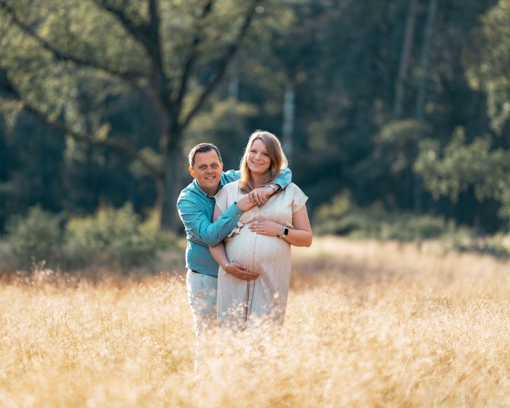 Couple shares playful moments together in a sunlit golden field.