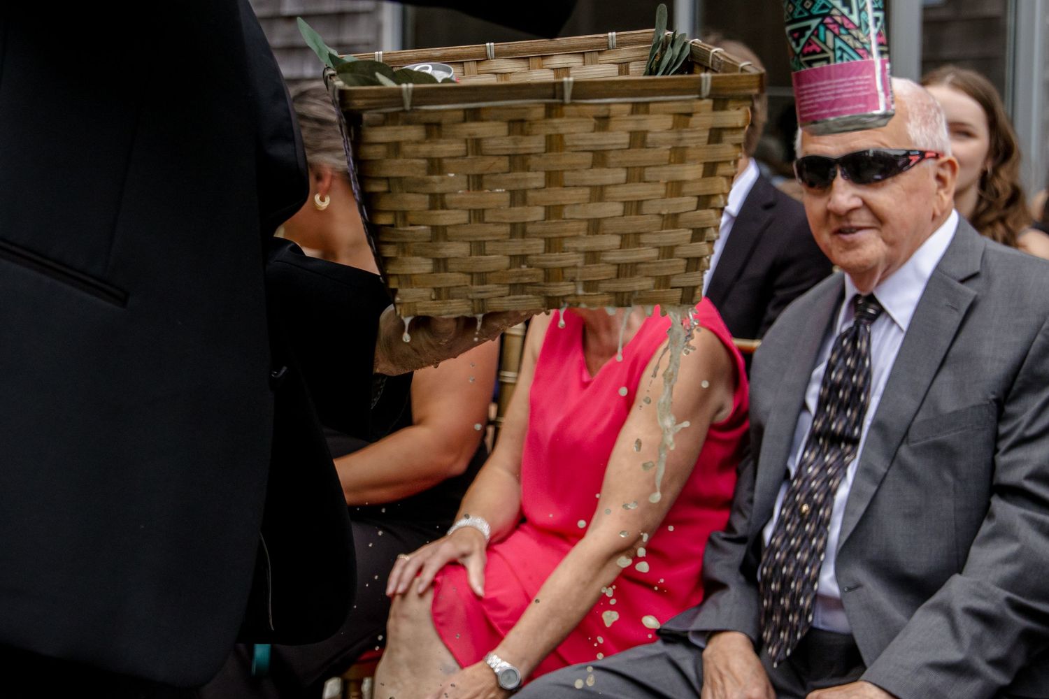A close up of someone passing out beers during a wedding ceremony, but the beers have leaked out of the carrying basket.