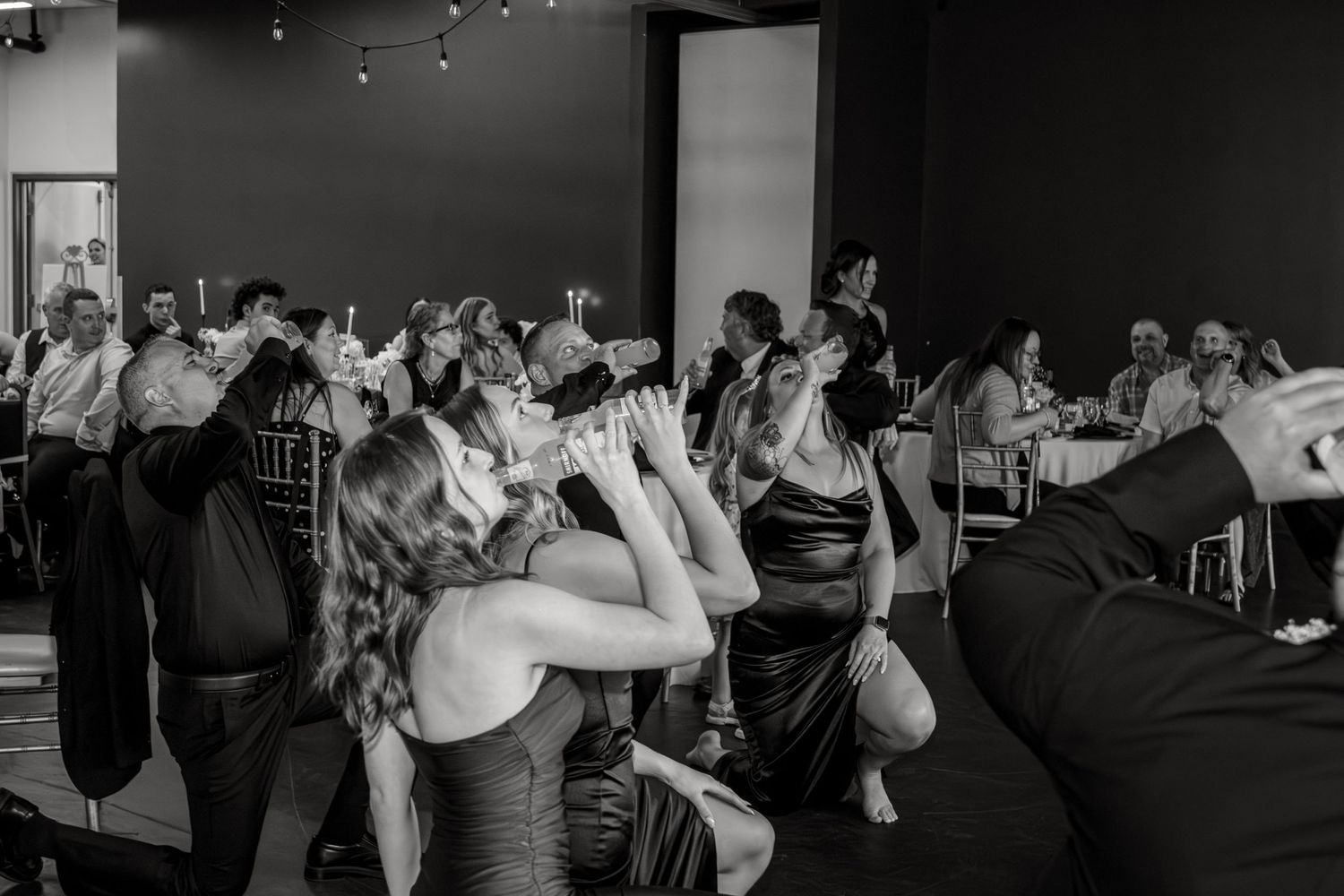Wedding party guests dance and celebrate together on a crowded dance floor in black and white photography.