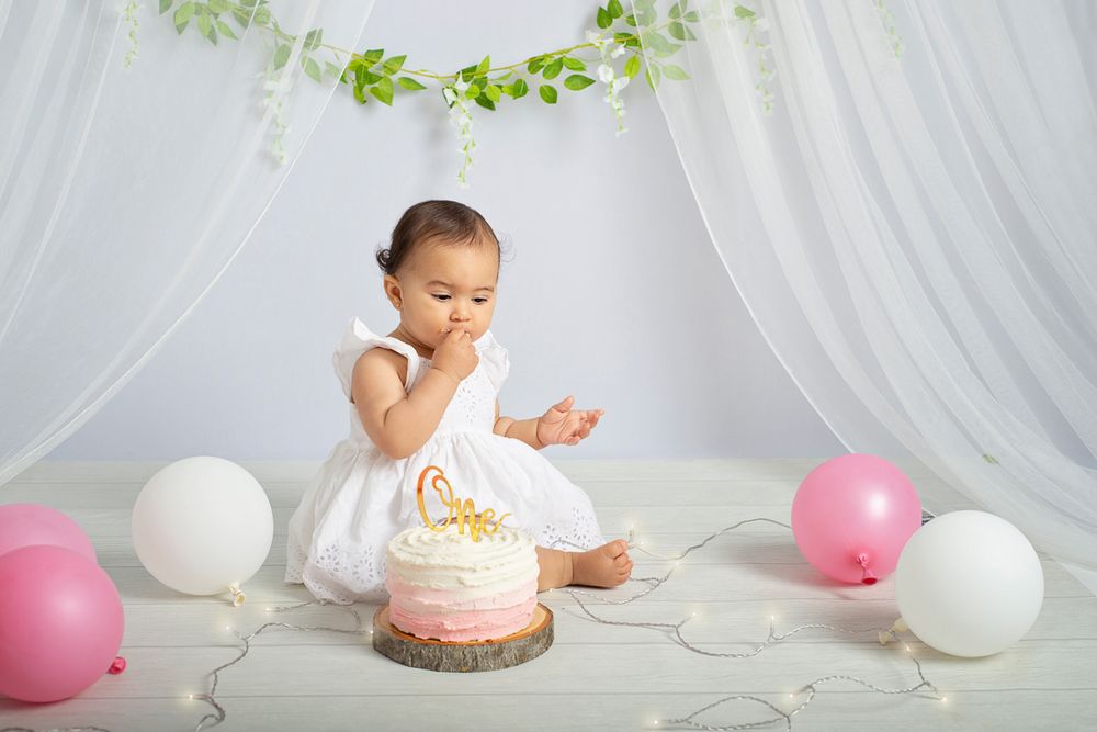 Cake session session for one year old baby girl with white shear curtains and pink and white balloons in studio Baltimore Ontario*