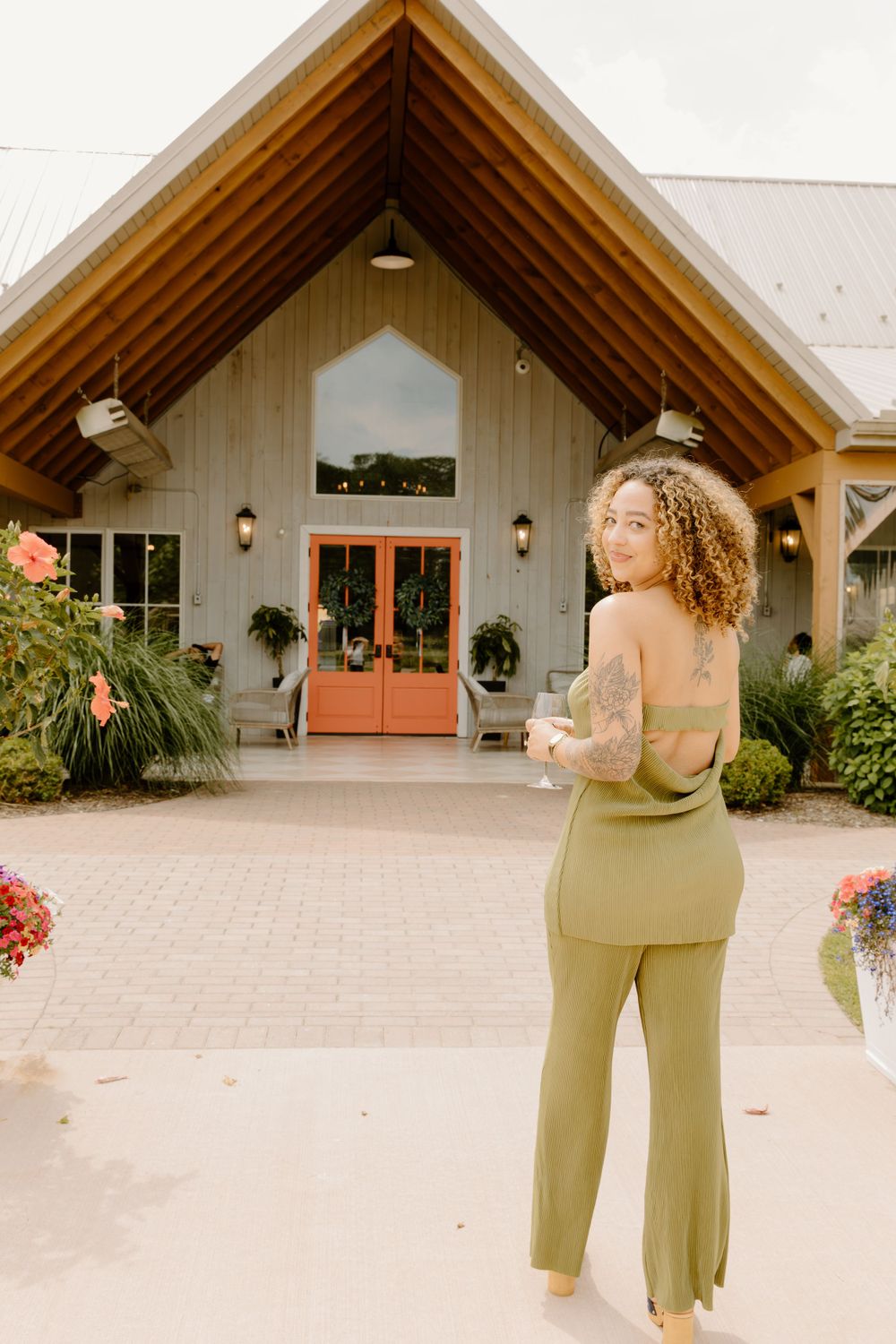 Modern venue exterior with orange double doors and landscaped garden entrance.