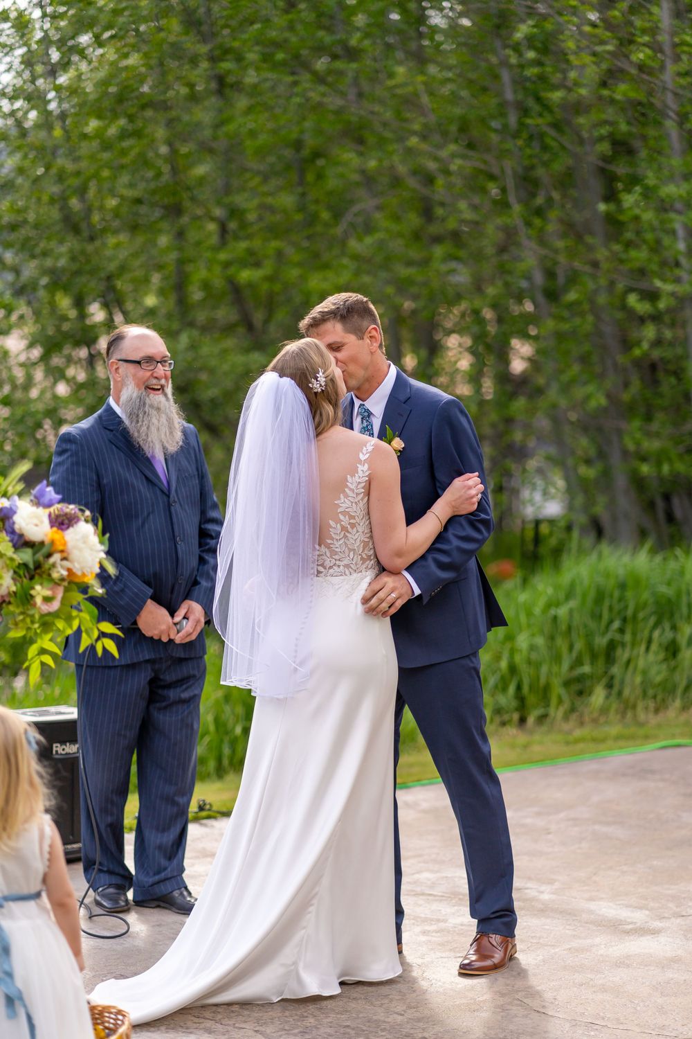 Intimate outdoor wedding ceremony moment with elegant white dress and navy suit.