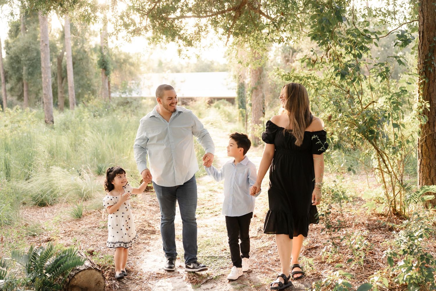 A family walks together on a wooded path during a golden sunset photoshoot in nature.