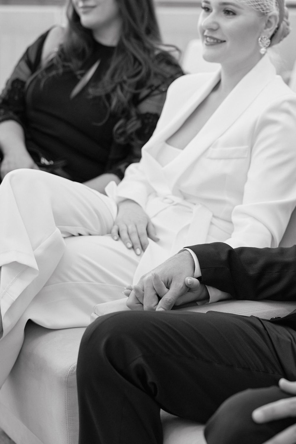 A black and white photo showing people sitting together, with one wearing an elegant white suit and another in dark attire.