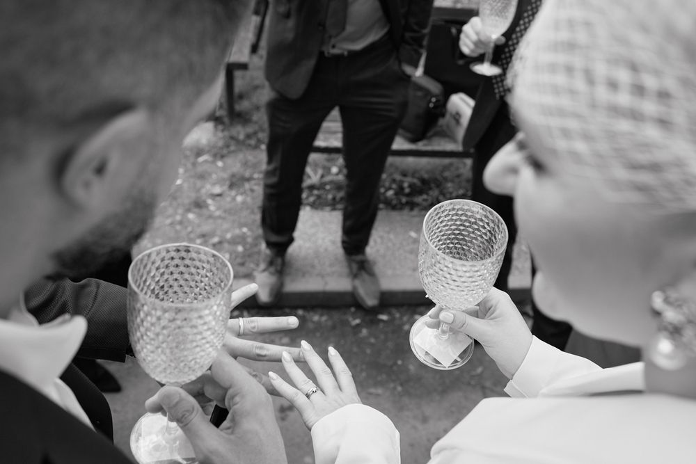 Black and white photo of hands pouring drinks into crystal glasses at an elegant bar service event.
