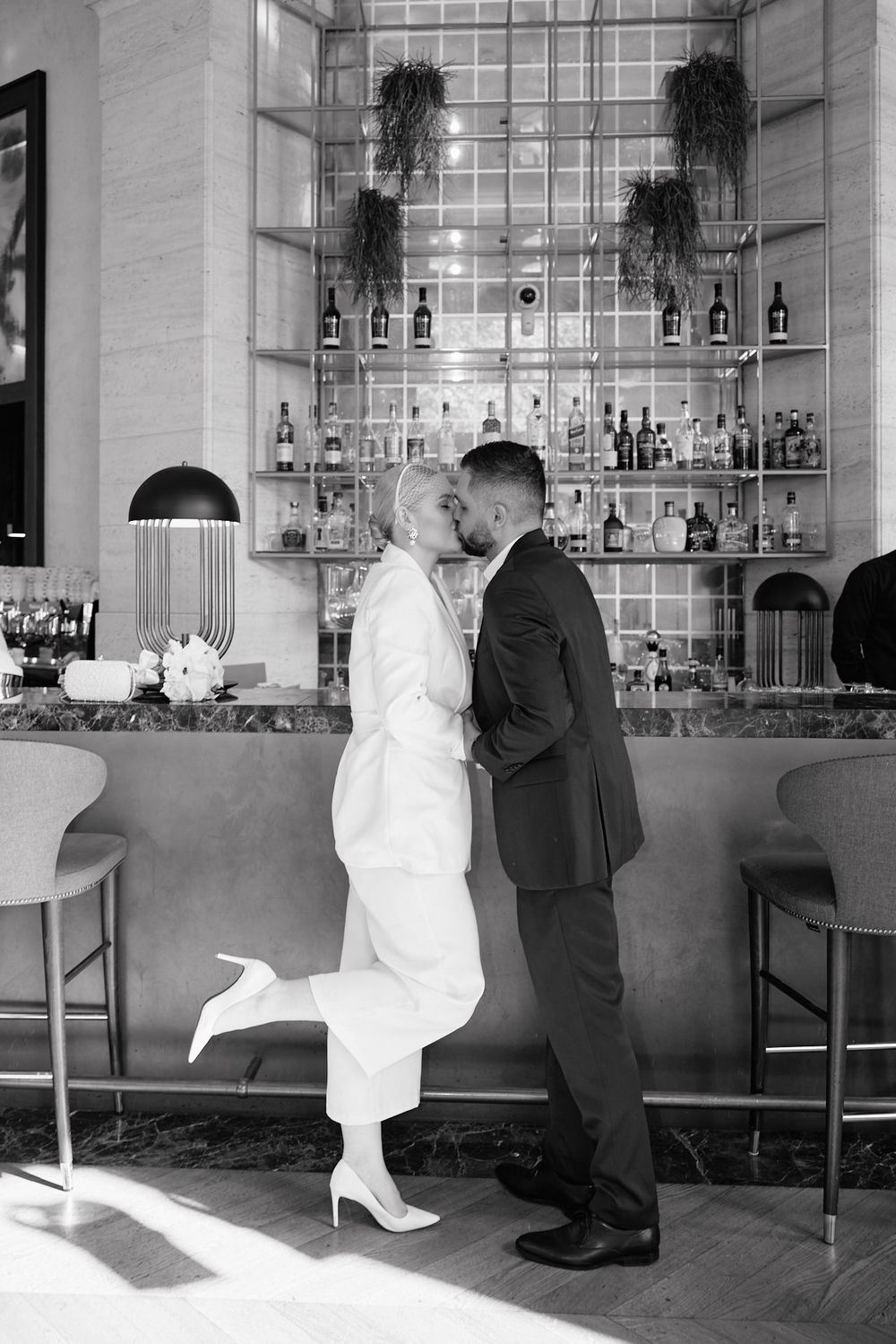 Black and white photo series capturing moments of a bride and groom interacting at an elegant bar venue.