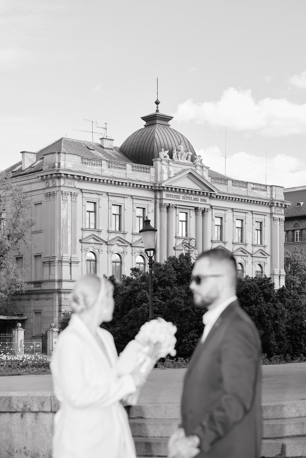 Black and white photo of a grand historic building with ornate architecture and dome in the background.