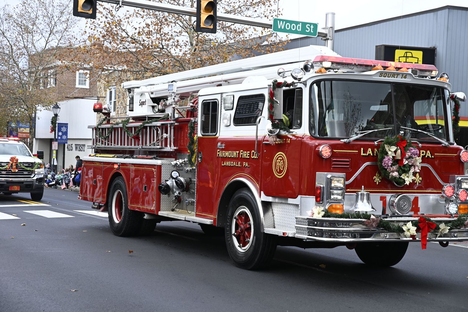Multiple red fire trucks and emergency vehicles are lined up on a snowy city street during winter.