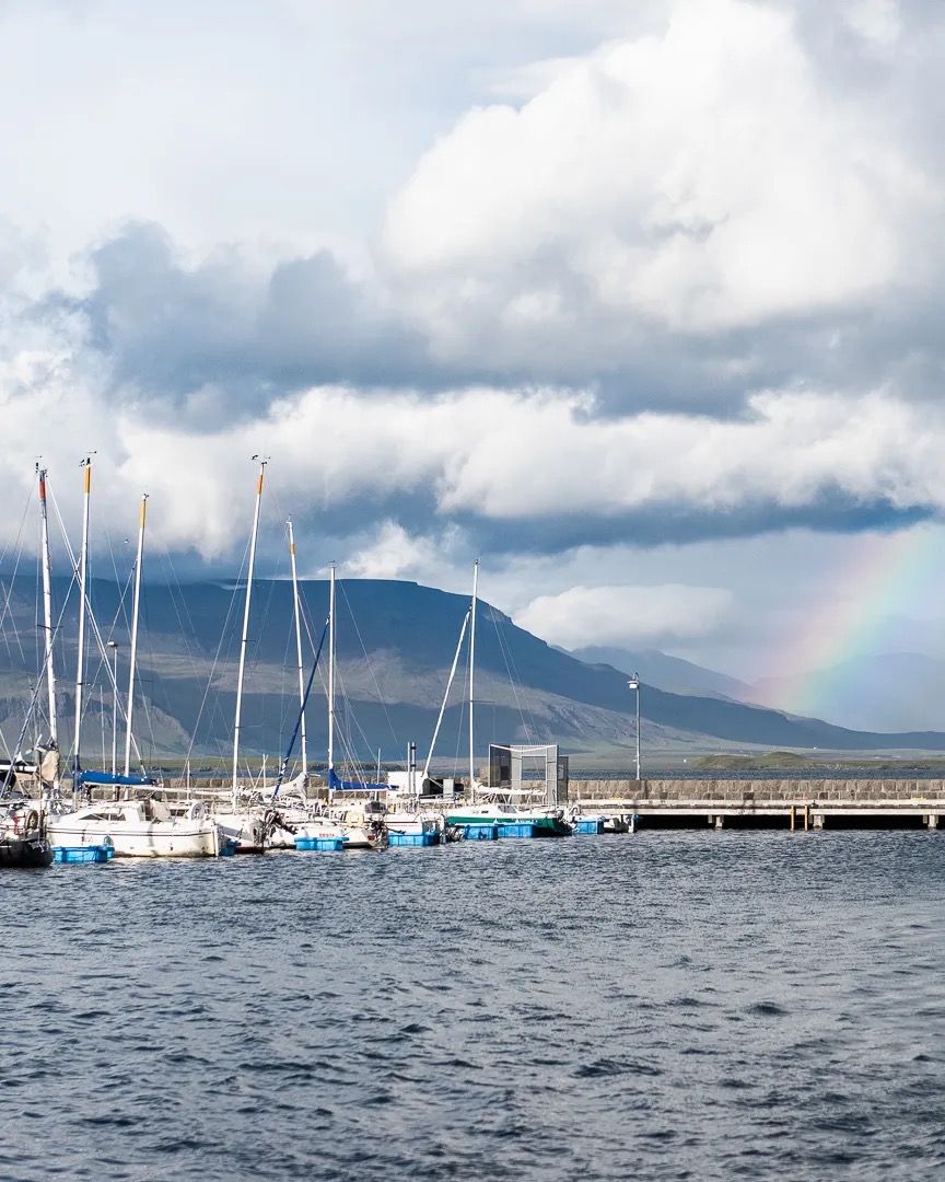 Boats moored on choppy water with mountains and dramatic clouds in the background.