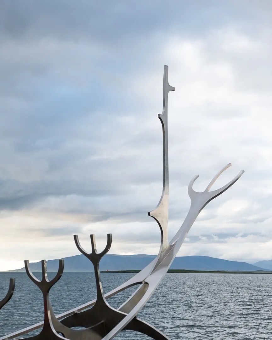 White antler-style sculpture boat against a cloudy sky overlooking the sea.