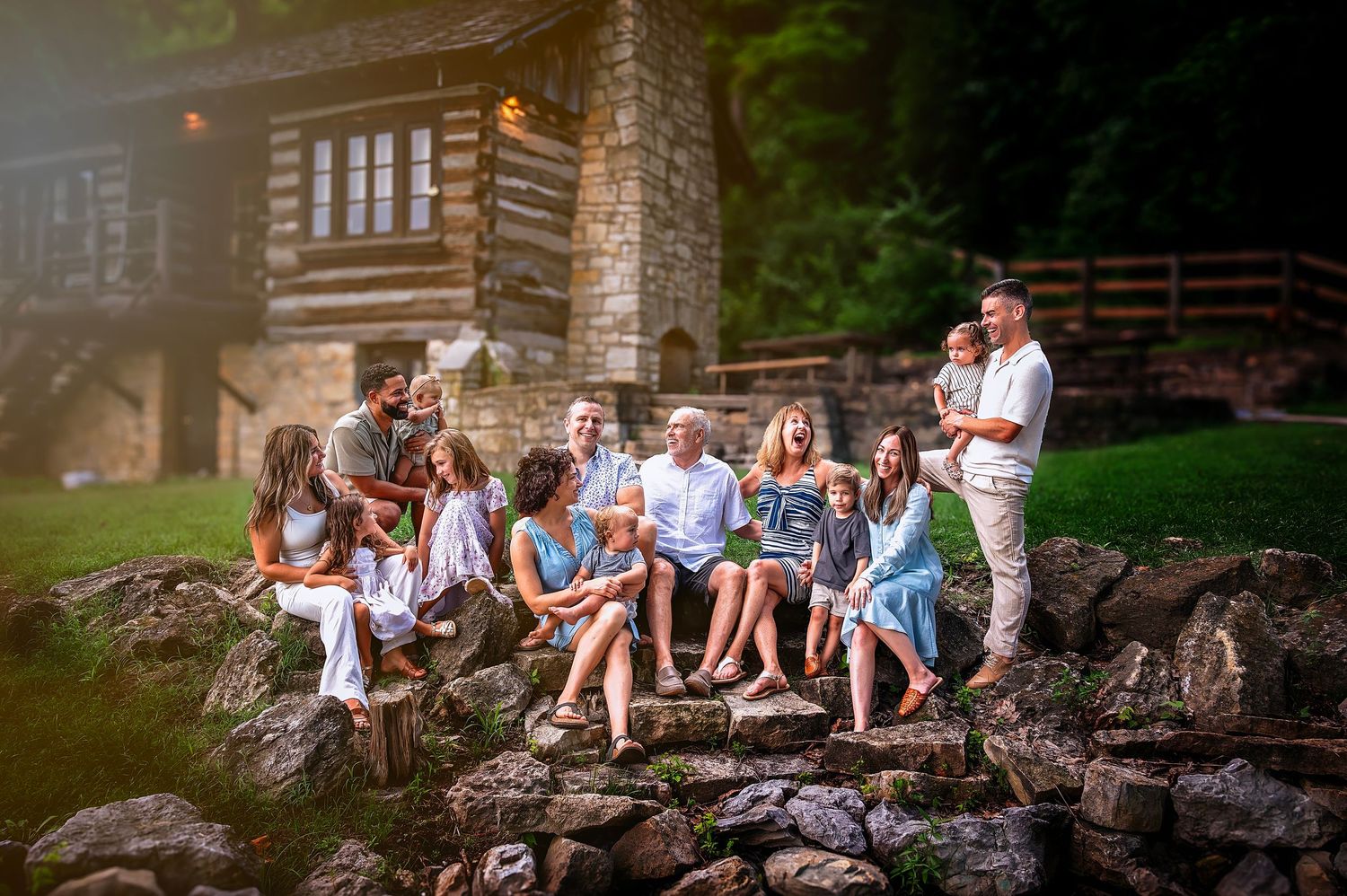 A group of people sit together on a rustic stone wall surrounded by lush greenery and trees.