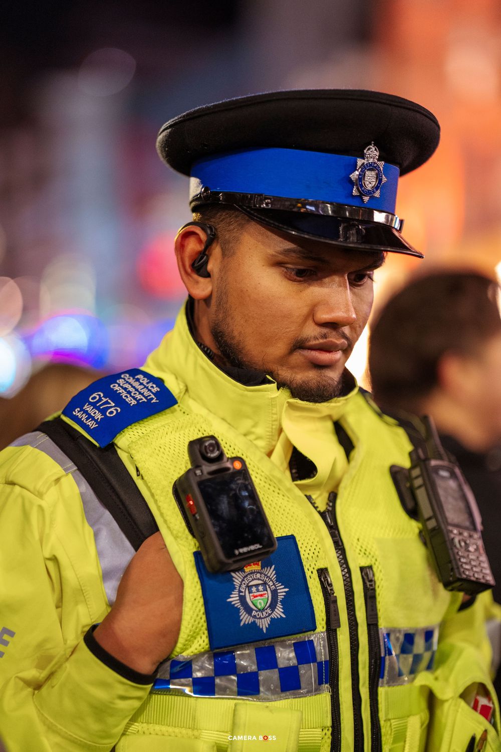 Police officers in high-visibility yellow jackets stand in formation during a nighttime patrol.