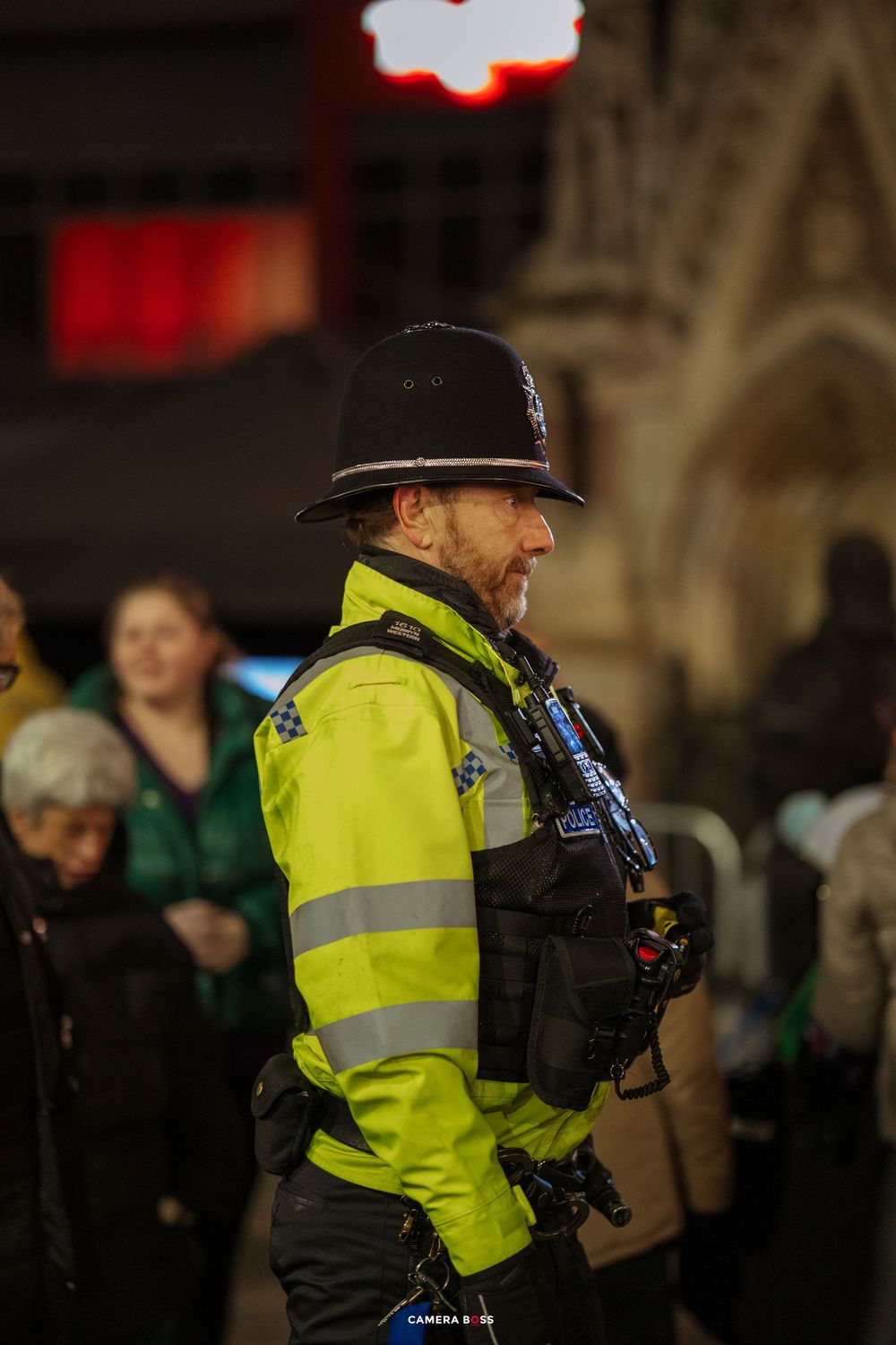 Police officer in high-visibility vest patrols a crowded nighttime event.