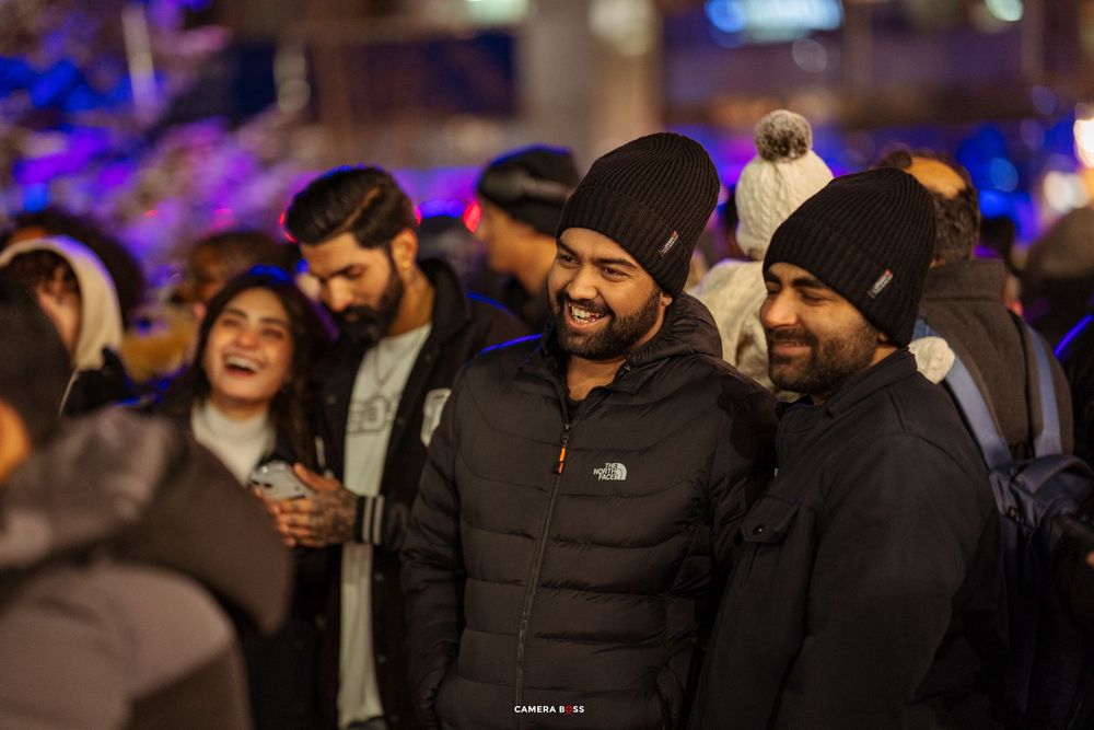 A group of friends enjoying a nighttime event with blue lighting and warm smiles in winter coats.