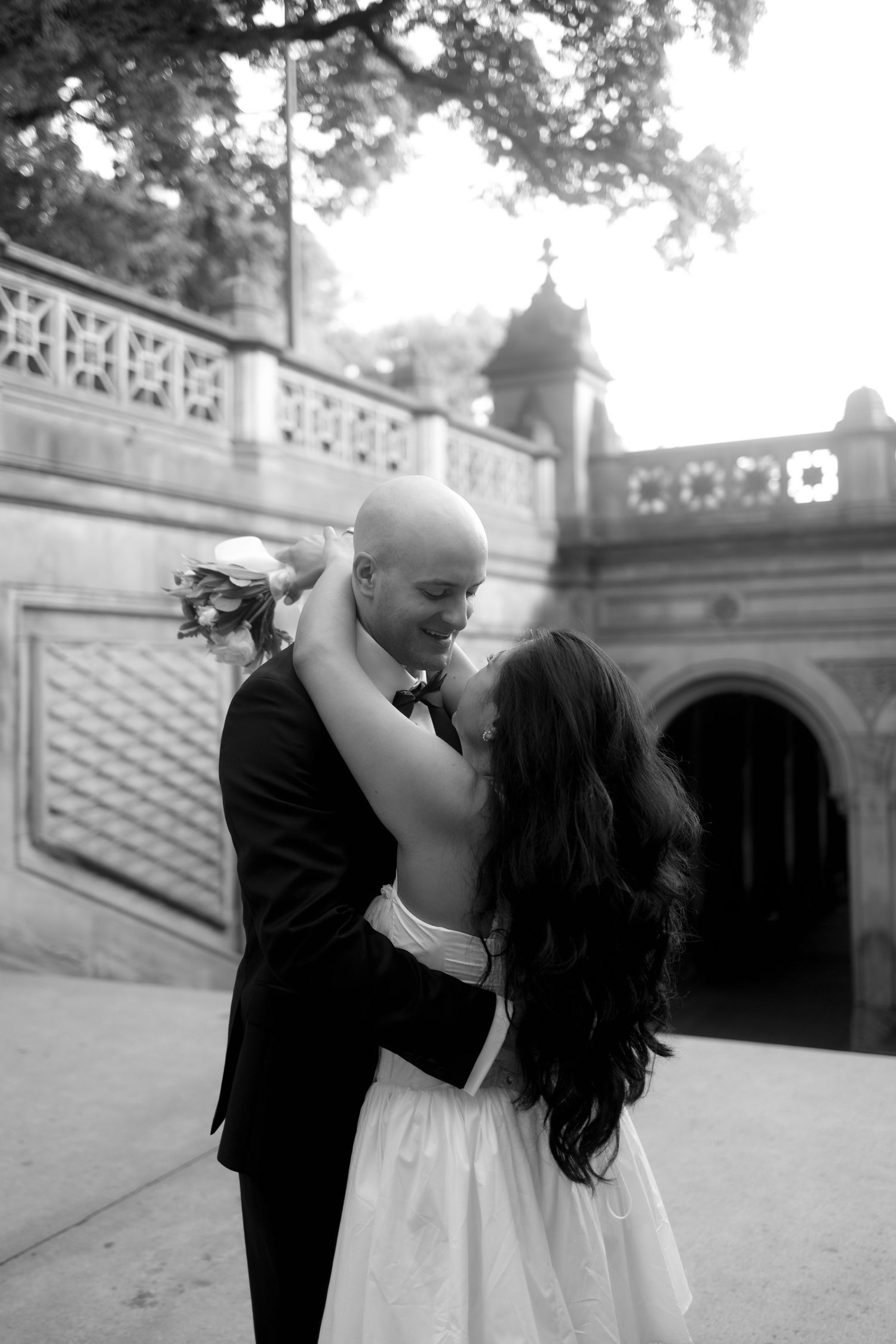 A romantic black and white photo series of a couple dancing and embracing on stone steps outdoors.
