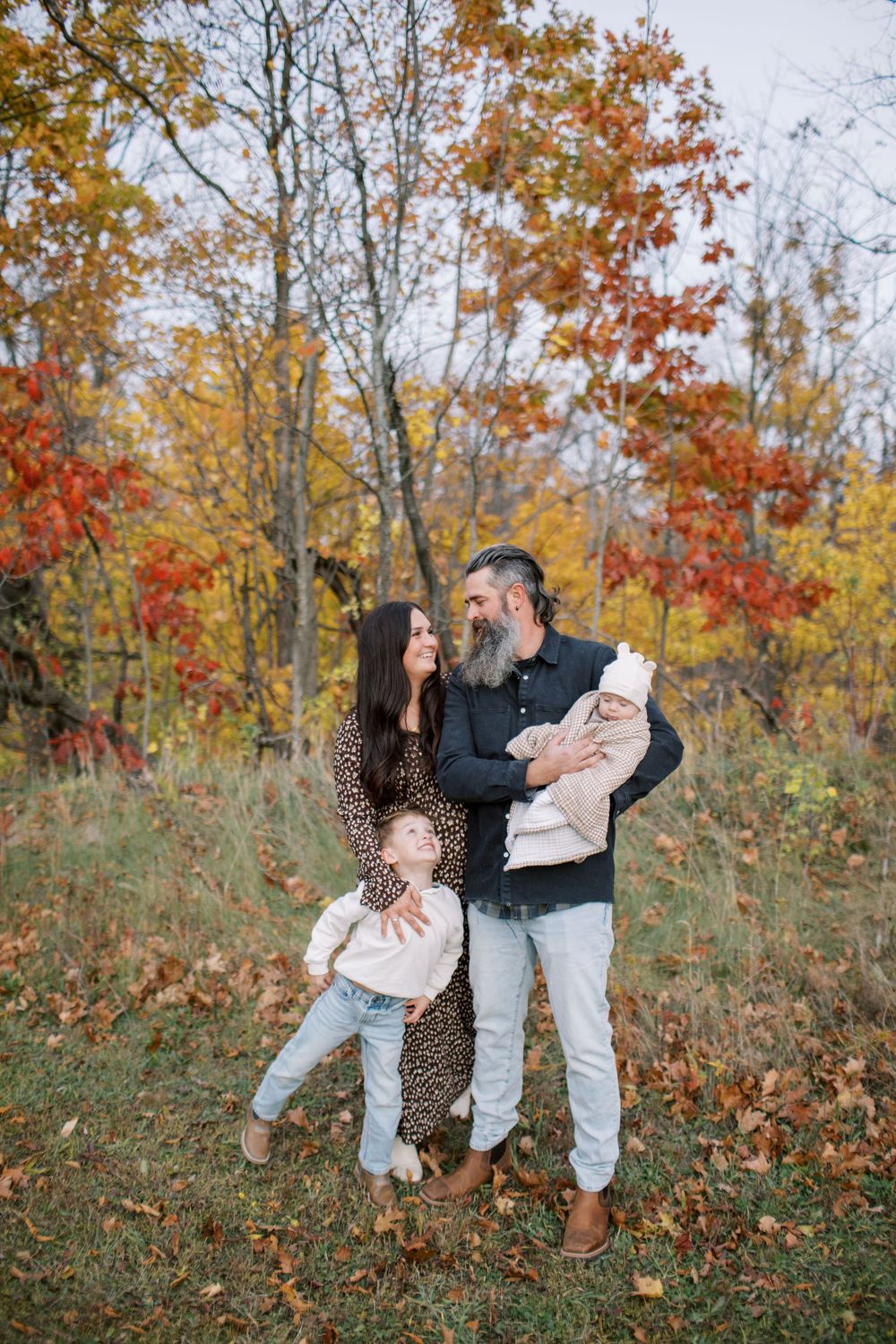 A playful autumn scene with people dancing and twirling among colorful fall foliage in a natural outdoor setting.