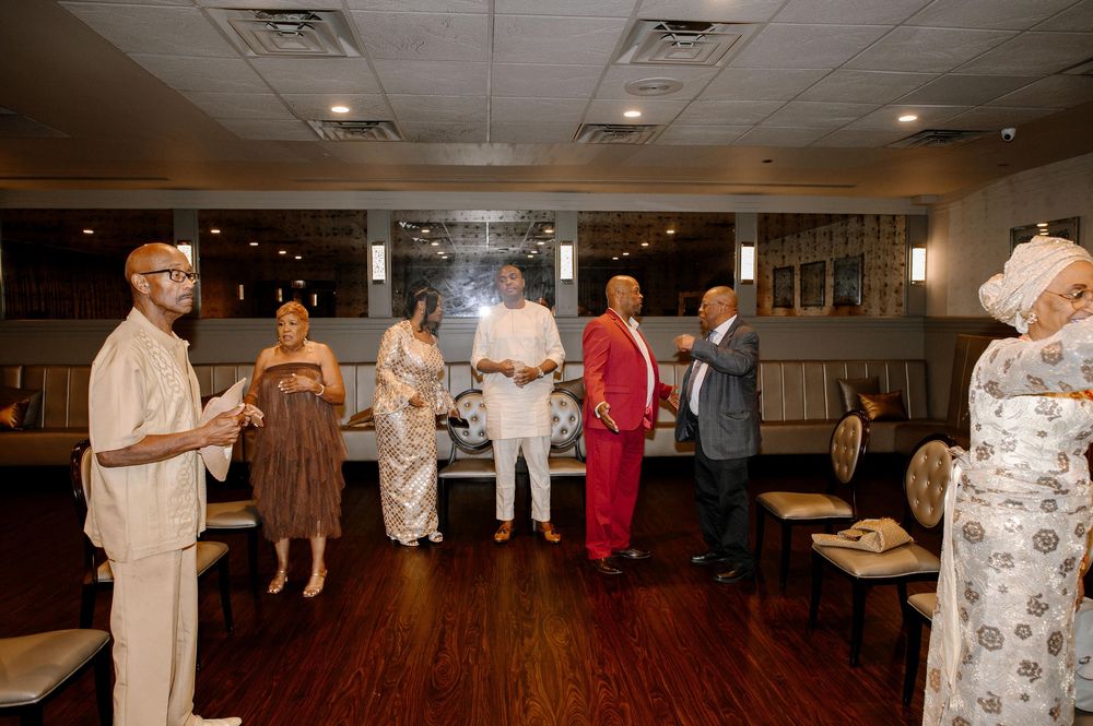 People dancing together at a social event in a community center with warm lighting and wooden floors.