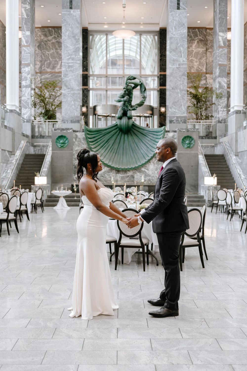 A couple shares a romantic dance moment in an elegant marble ballroom with green art deco fan decorations.