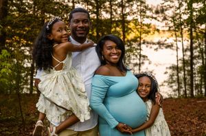 A joyful family portrait in the woods during autumn with a pregnant mother in Stafford VA.
