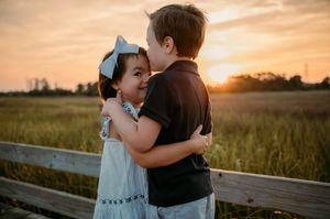 Two young children share a tender moment together on a boardwalk at sunset in Stafford VA.