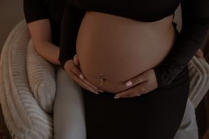 Close-up of a pregnant belly with hands gently resting on it in Stafford VA.