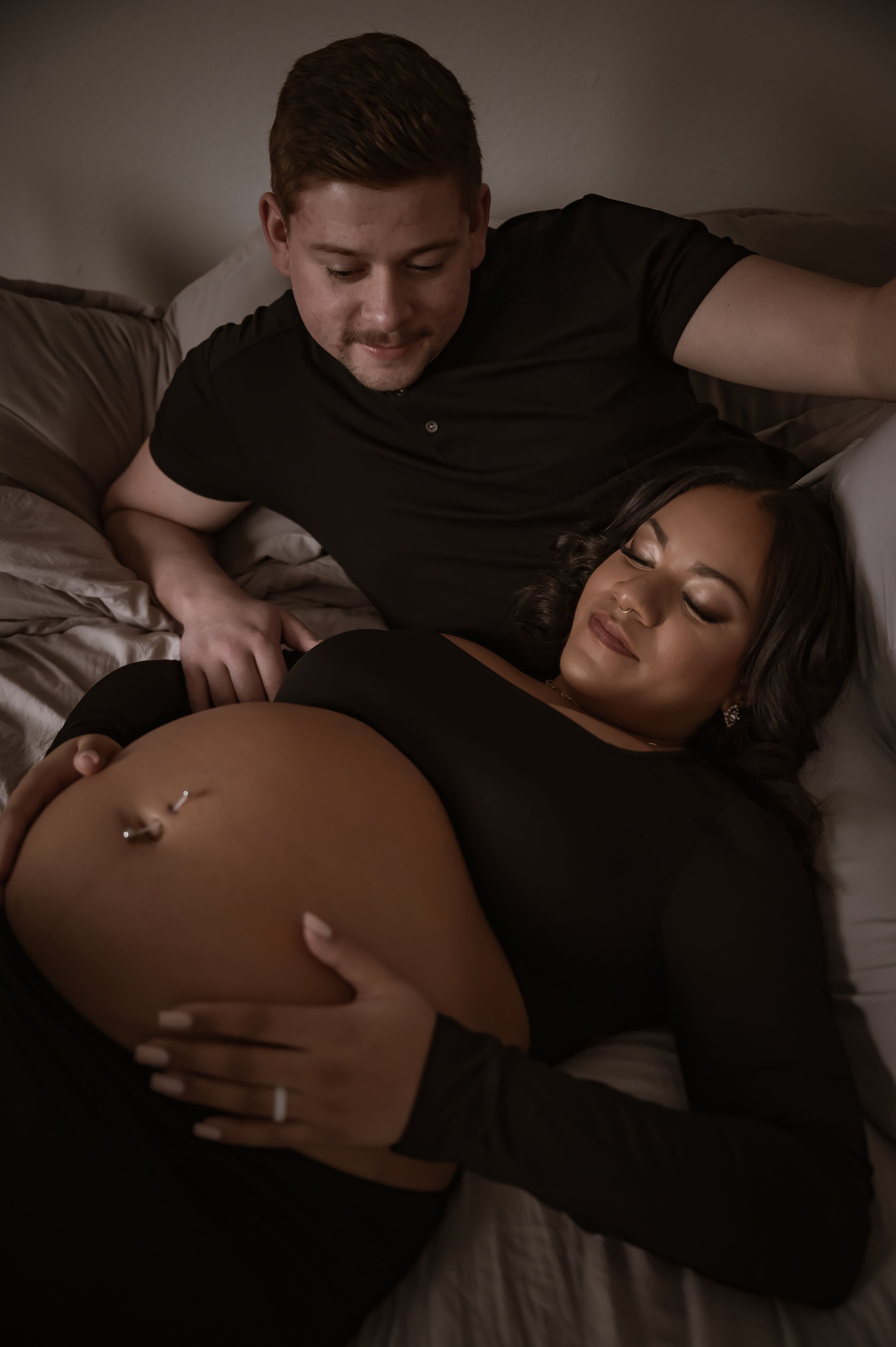 Intimate maternity photo of an expectant couple resting together on a bed in Stafford VA.