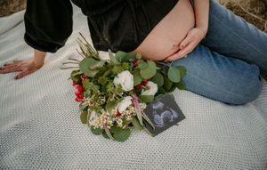 Maternity photoshoot details with ultrasound photos and floral arrangement on gray blanket in Stafford VA.