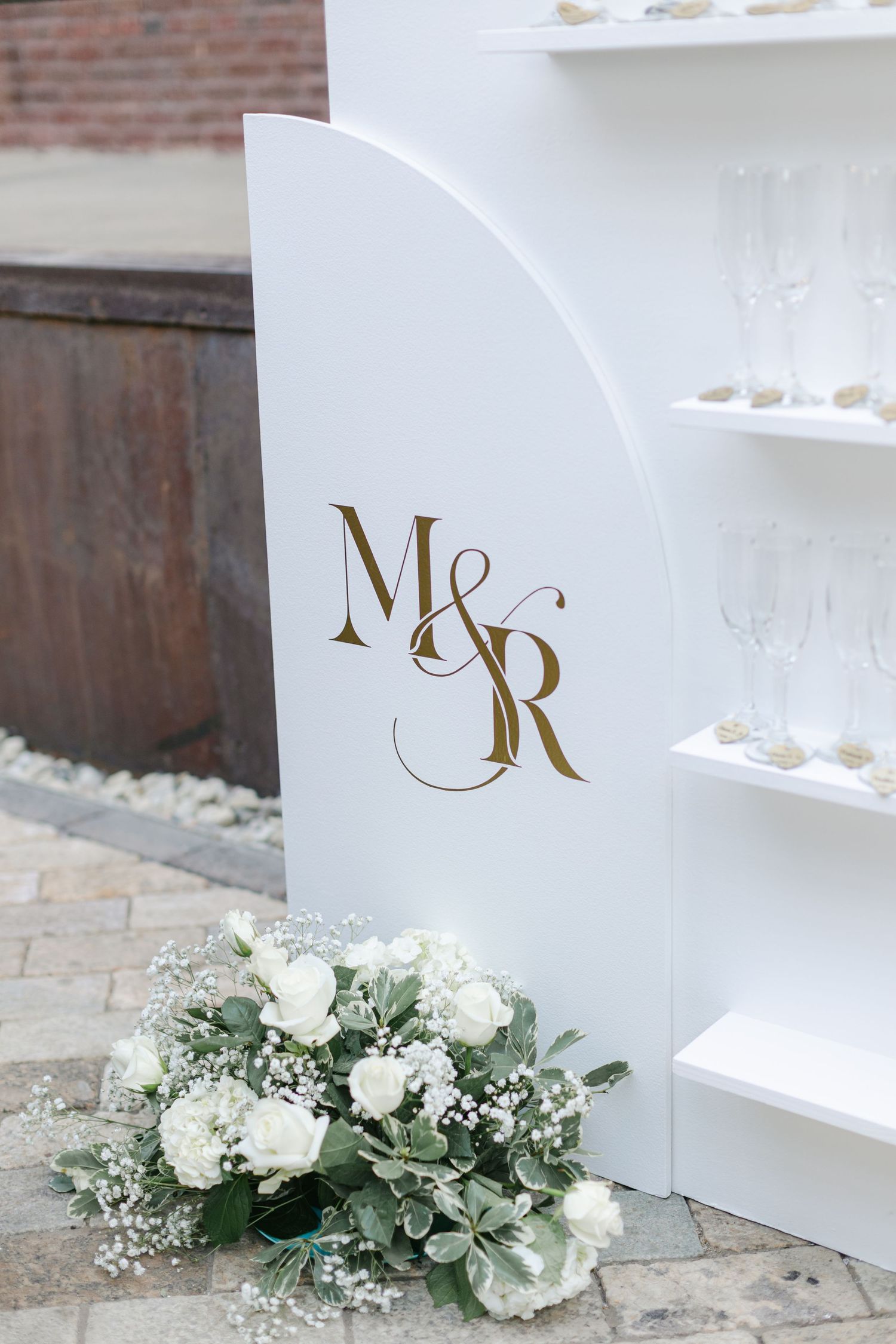 Wedding party celebrates with champagne under rustic brick archways at an elegant reception venue.