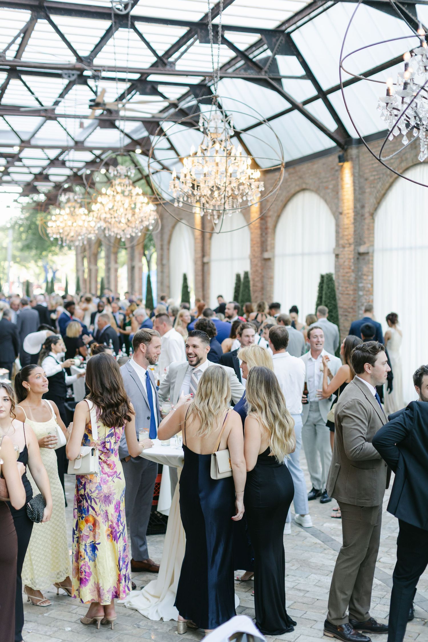 Wedding guests mingle and socialize in an elegant brick-walled venue during a reception.