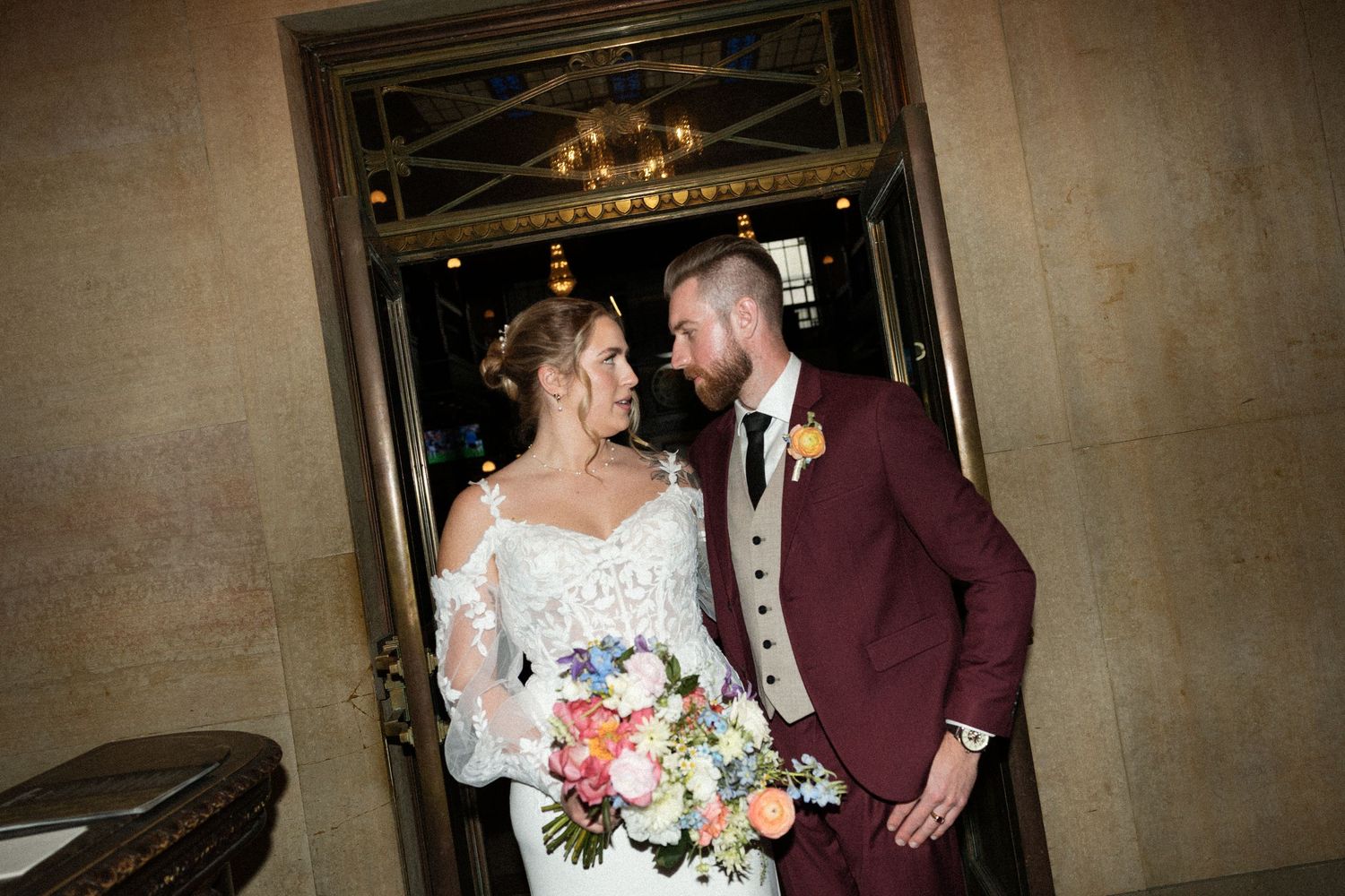 Bride and groom share intimate moments during their wedding photo session in an elegant venue with stone walls.