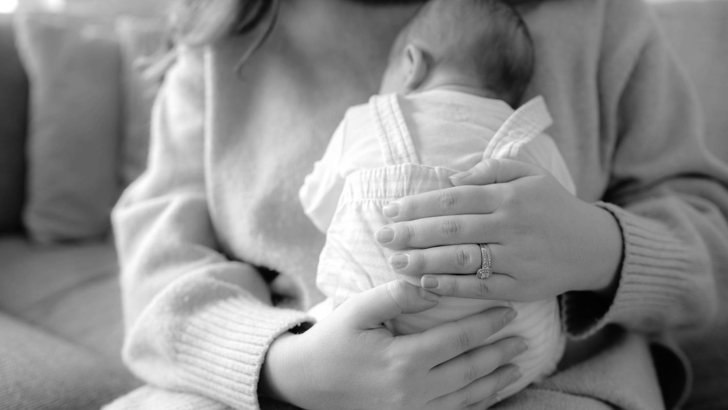 A series of black and white images showing hands holding a newborn baby.