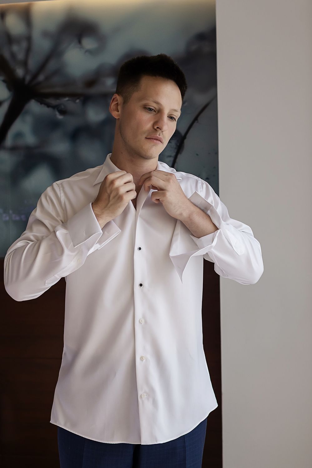 A series of photos showing someone in a white dress shirt adjusting their collar and tie against a dark background.