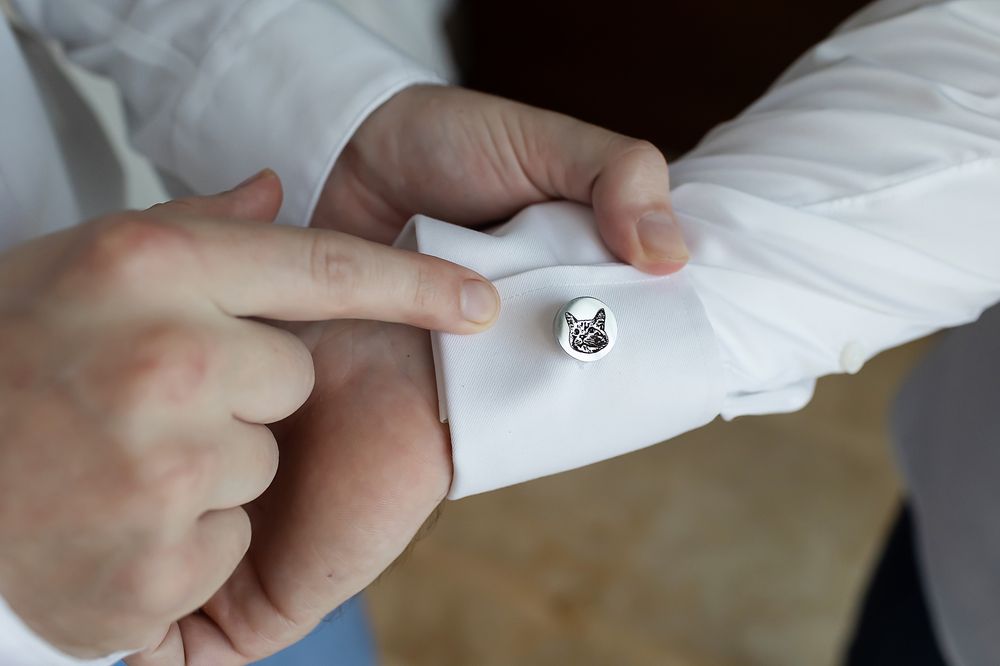 A person rolls up a white dress shirt sleeve, showing the step-by-step process of folding the cuff neatly.