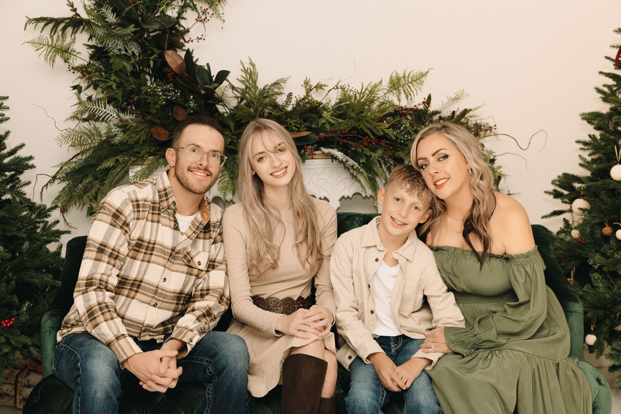 Christmas family pictures of a family of 4 sitting down in an indoor studio in Greeley Colorado. pictures of 2 kids and 2 parents smiling