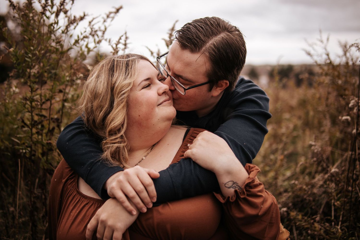 A couple shares intimate romantic moments in a field during golden hour as seen in multiple connected photos.