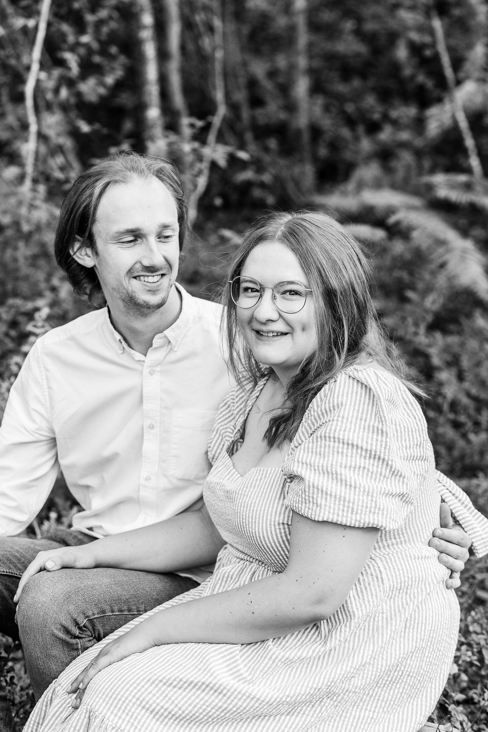 A couple sitting together outdoors sharing joyful moments in black and white photography.