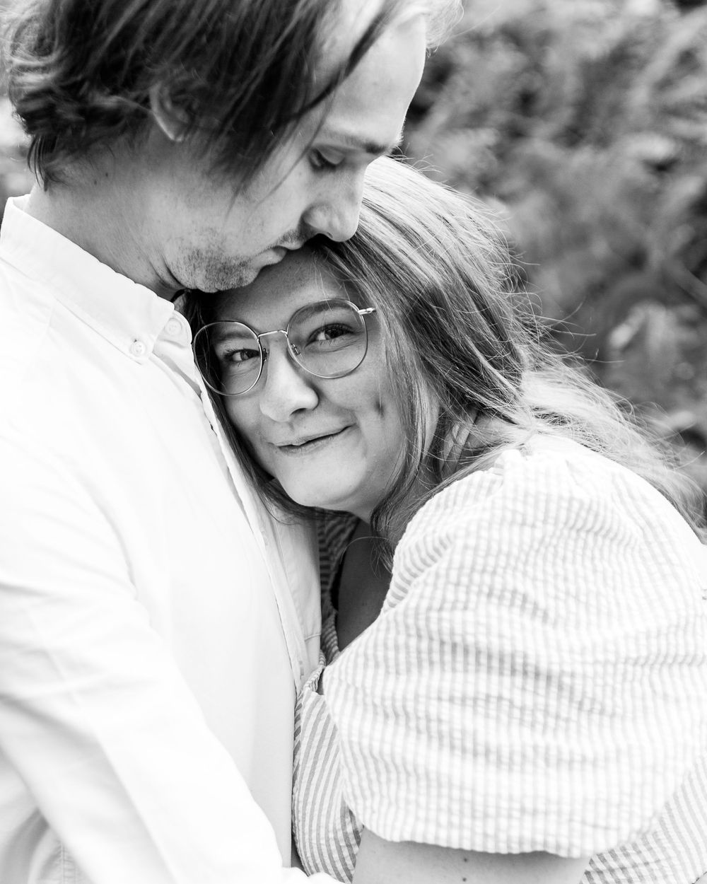 A romantic black and white photo series showing a couple embracing and sharing intimate moments outdoors.