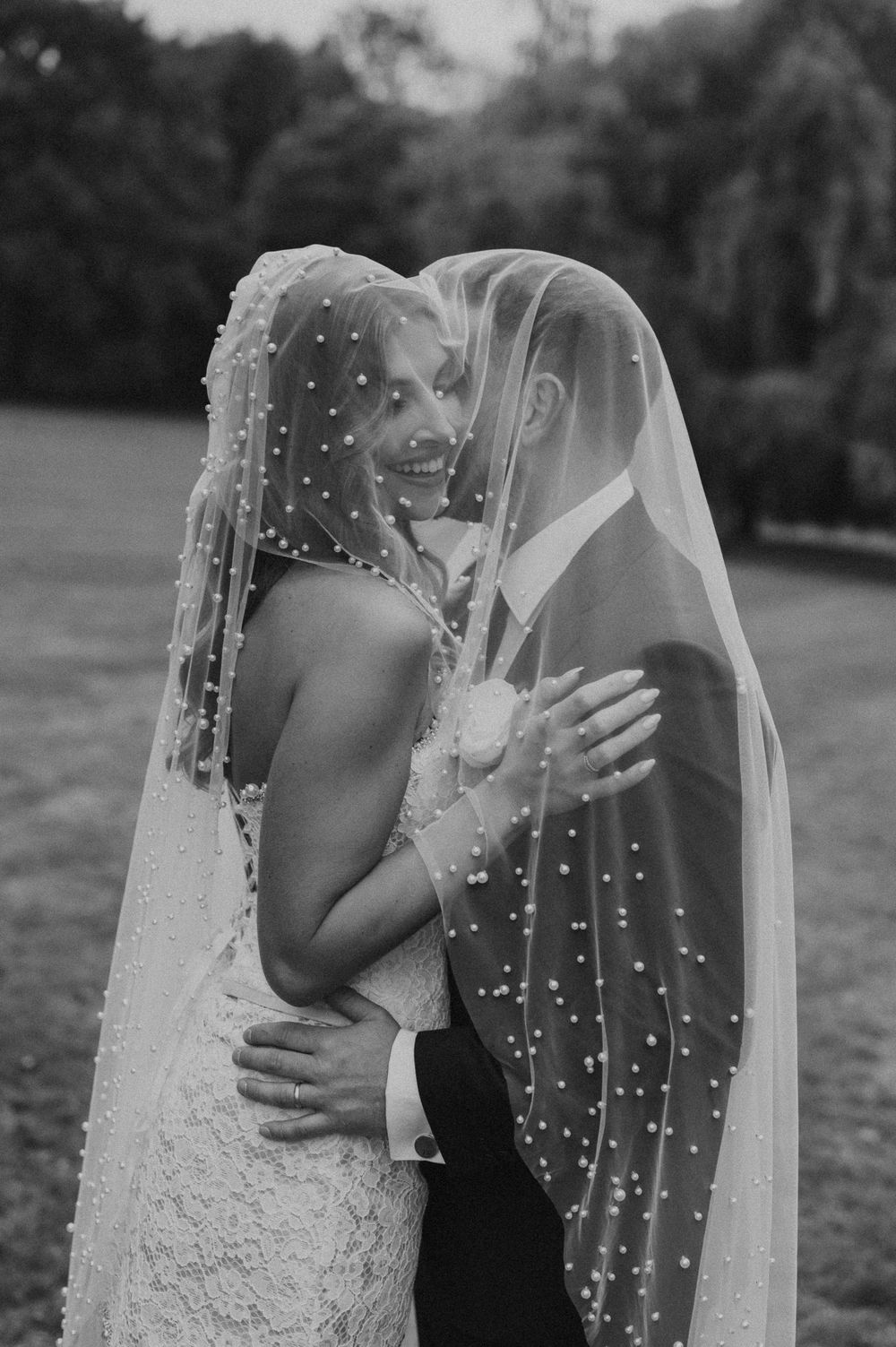 A romantic black and white wedding photo sequence showing a couple sharing an intimate kiss under a pearl-studded veil.