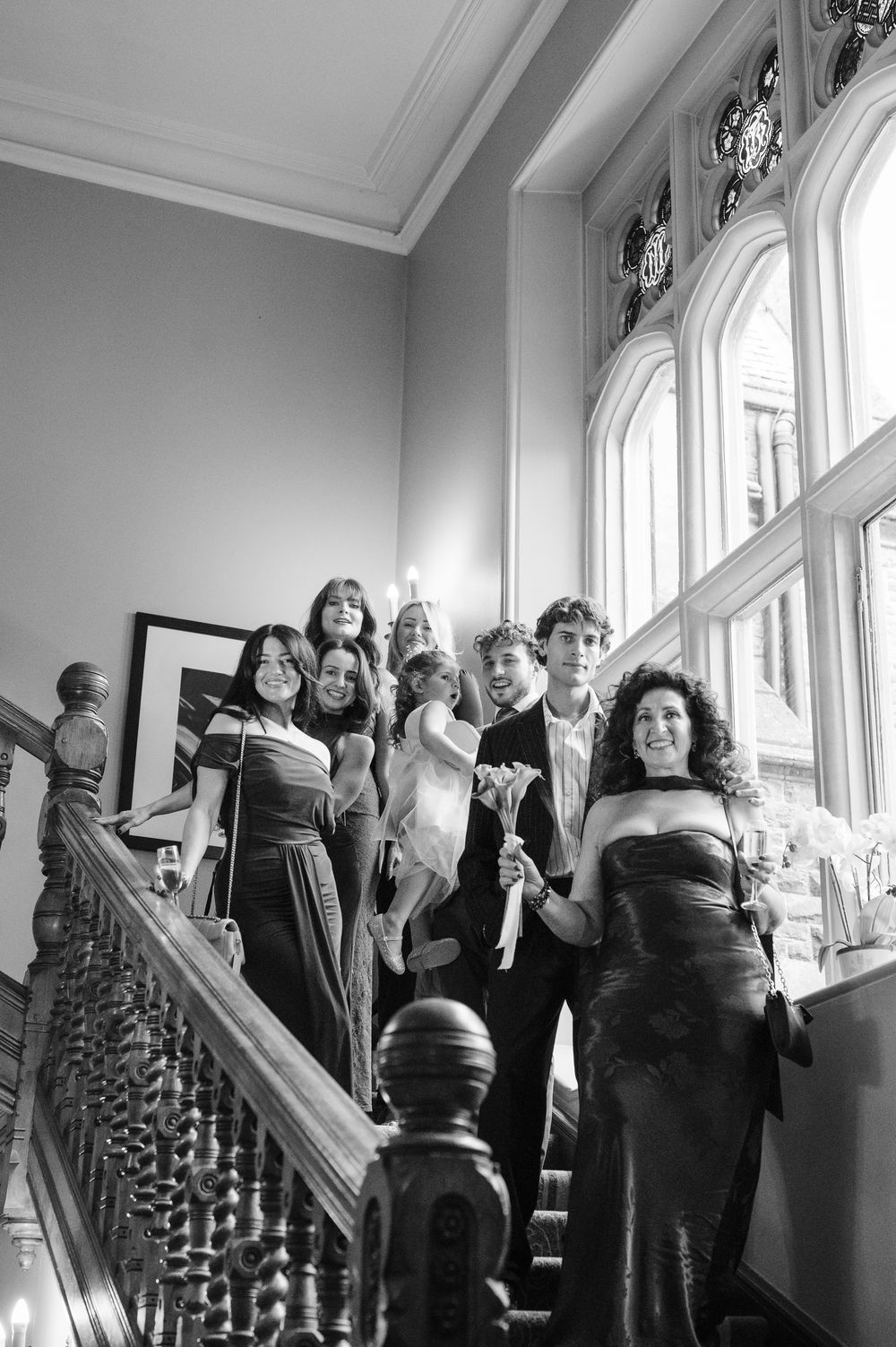 A black and white photo series showing people gathered on an elegant staircase during what appears to be a social event.