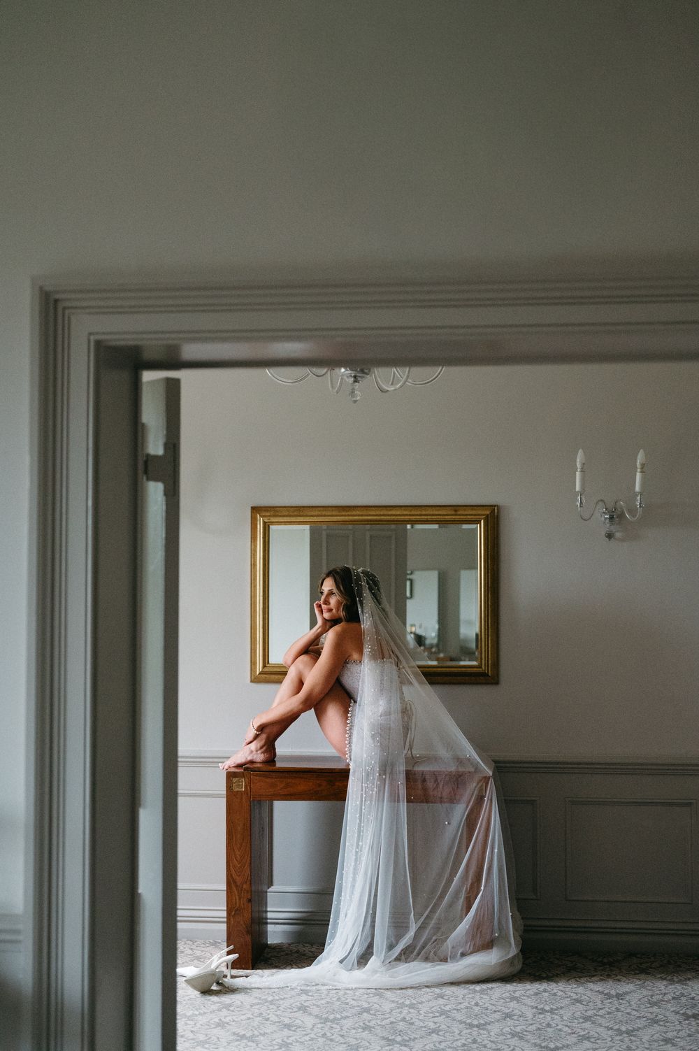 A series of connected boudoir photos showing a bride in white lingerie and veil posing elegantly against interior walls.