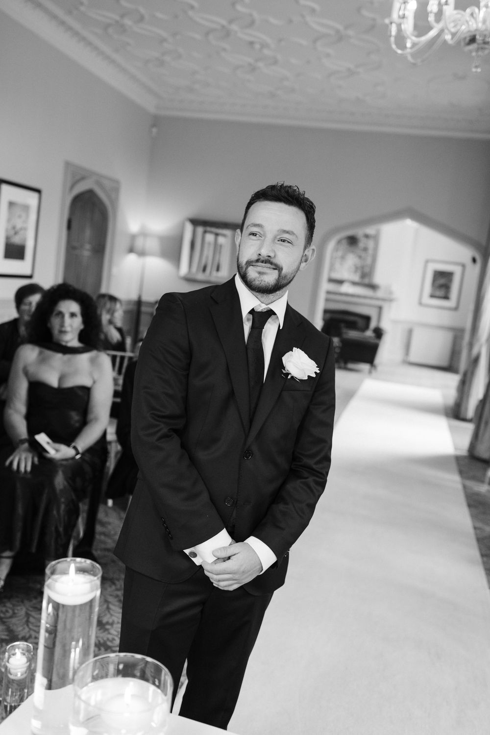 Black and white photo series showing groomsmen in formal suits at an elegant wedding venue with ornate decor.