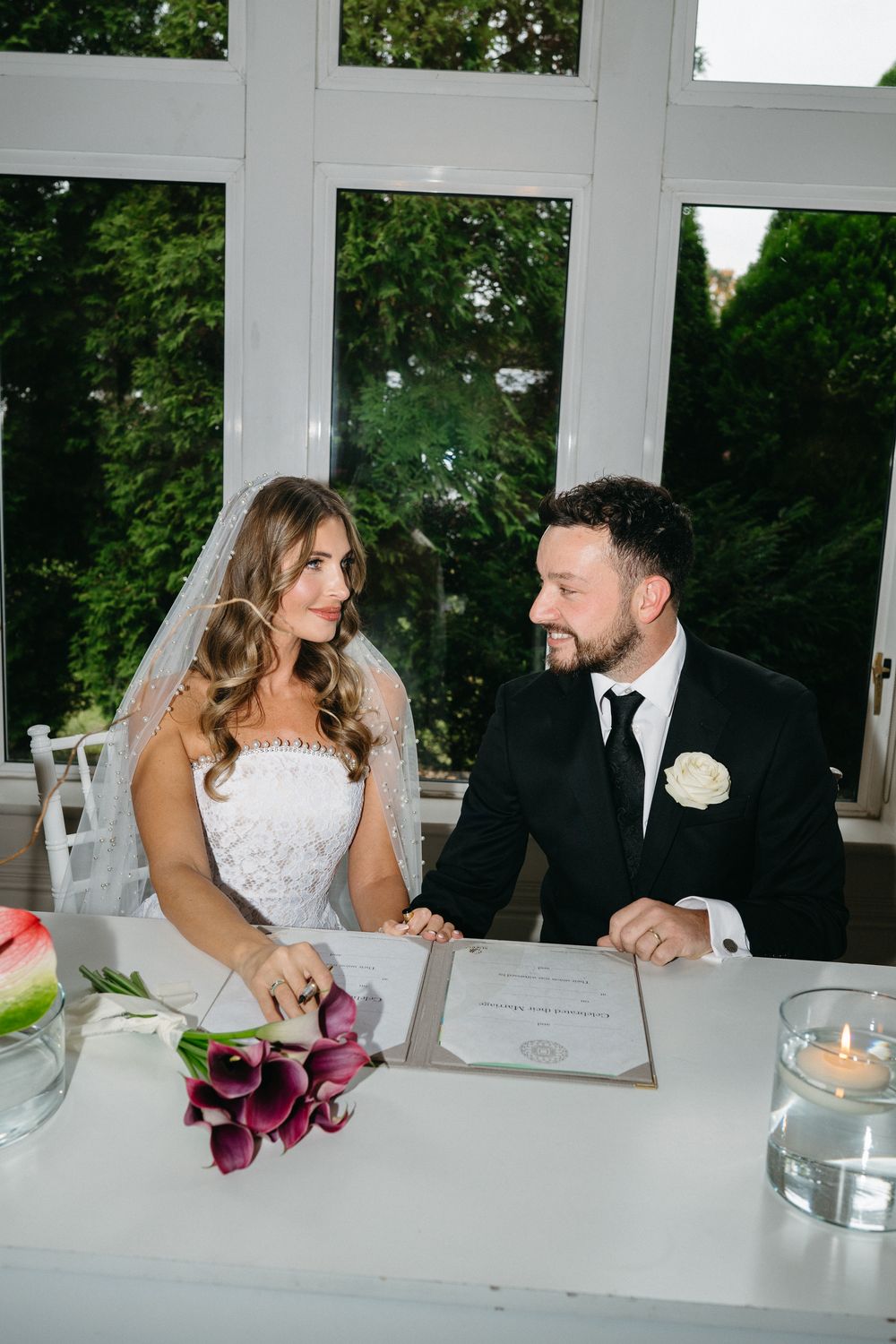 A bride and groom share intimate moments at their wedding reception table decorated with candles and flowers.