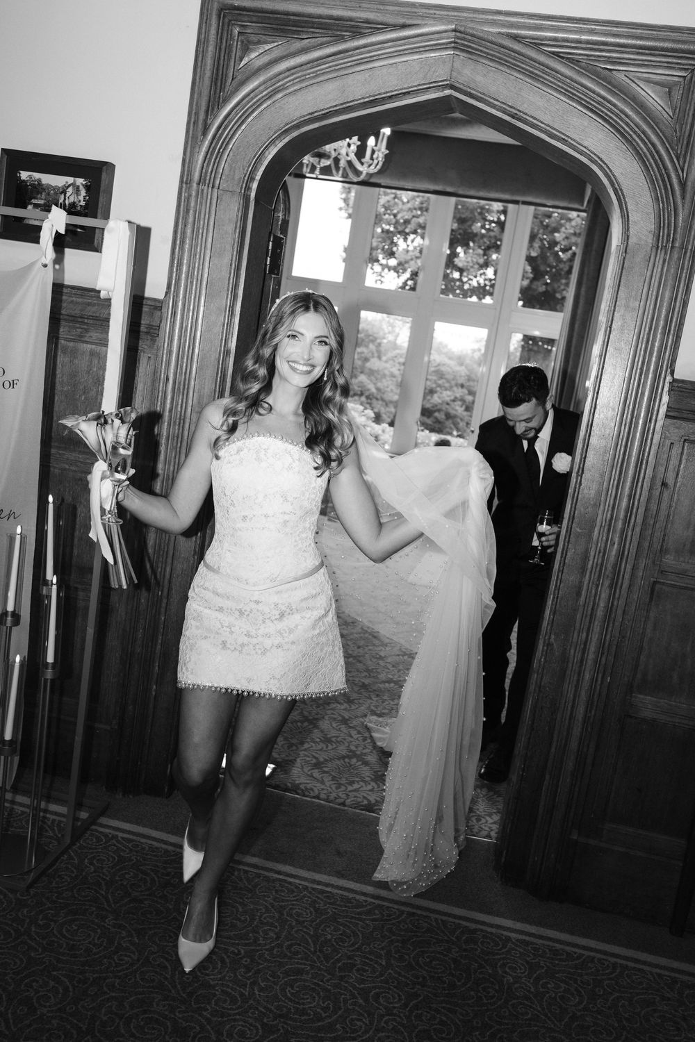A series of black and white photos showing a bride and groom playfully peeking around elegant arched doorways.