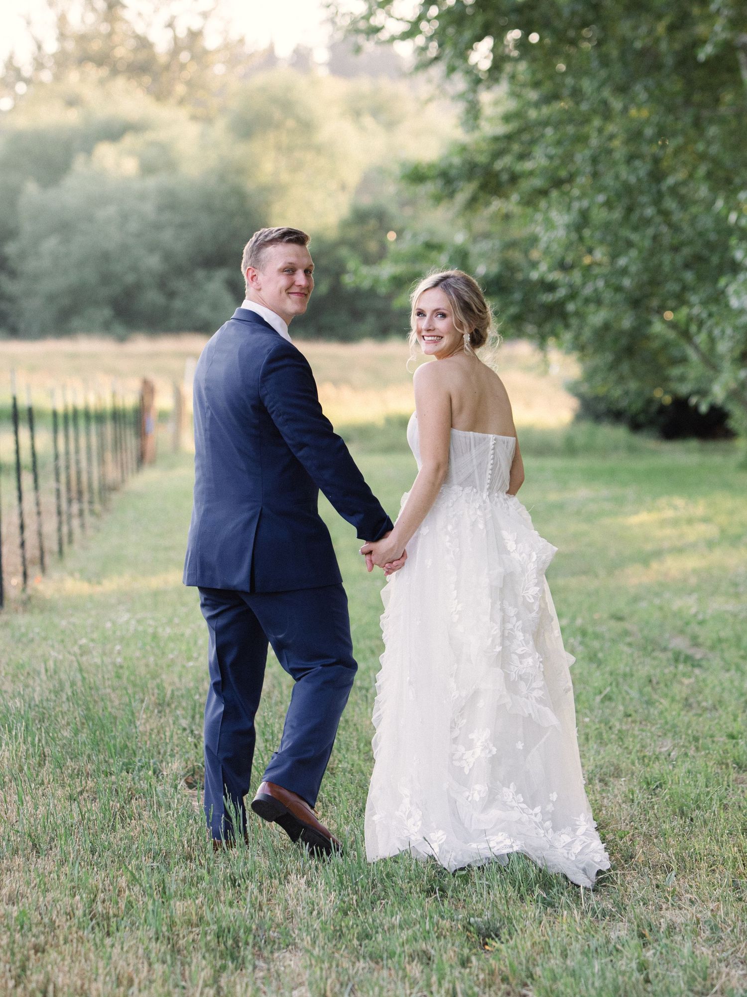 A couple shares an intimate moment at their outdoor wedding, with the bride in lace and groom in navy suit.