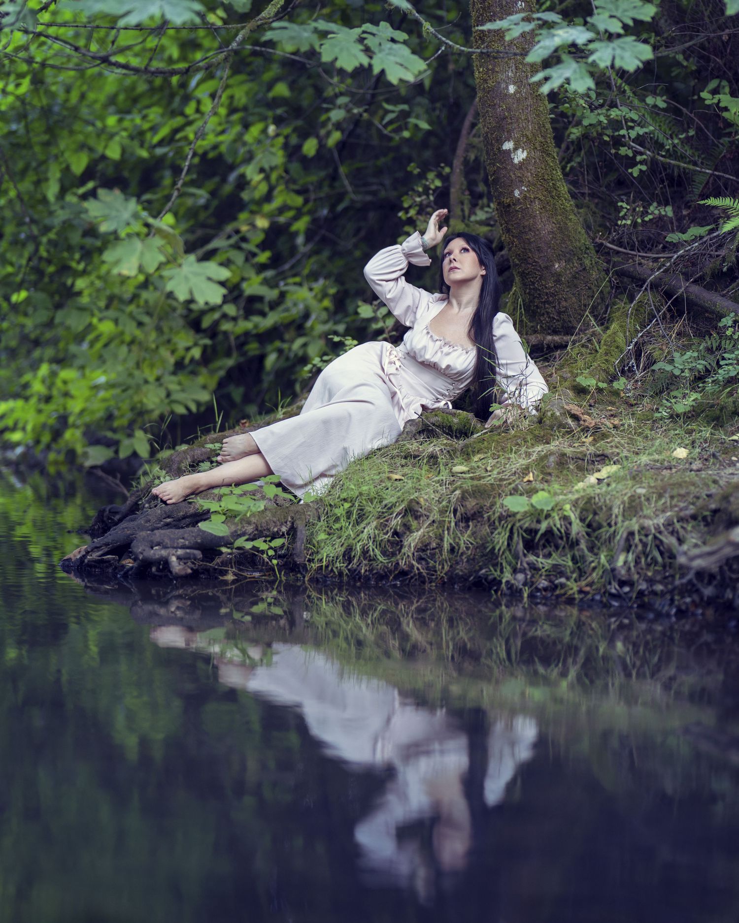 A series of four moody photos show a figure in a red dress lying dramatically on a dark ground against a misty backdrop.