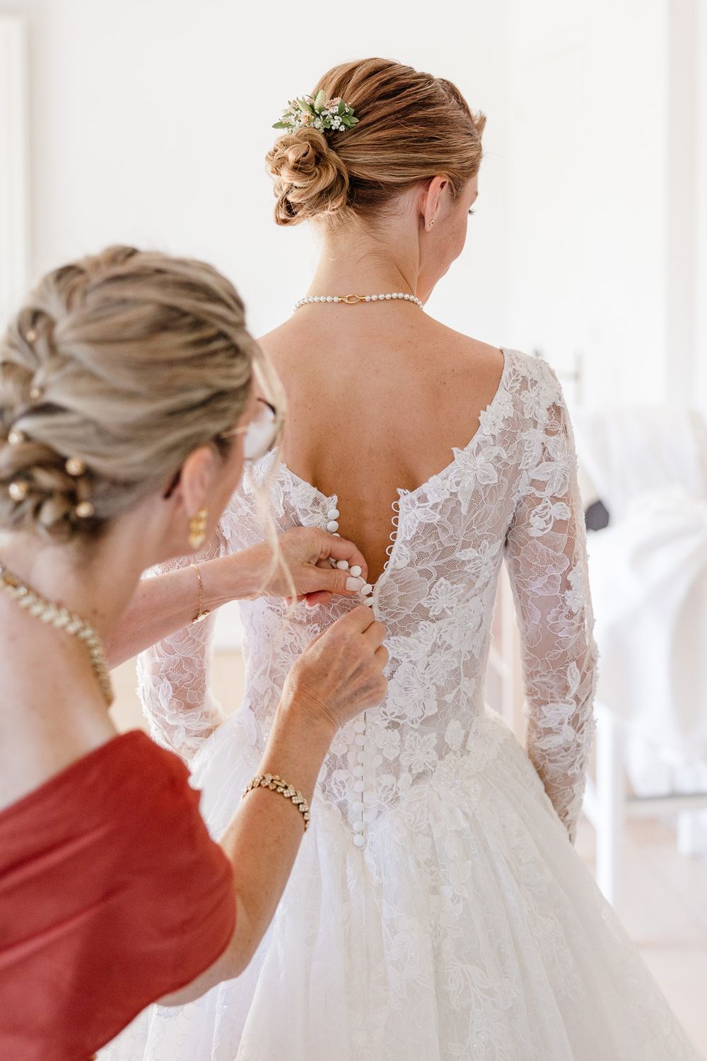 Mere de la mariee boutonne le dos de sa robe avant la ceremonie a Lille, un moment cle du reportage photo de mariage pour les maries.