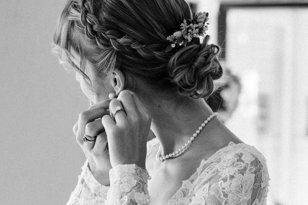Reportage mariage Lille : mariee ajuste sa boucle d'oreille pendant les preparatifs avant la ceremonie et la reception au chateau du Biez